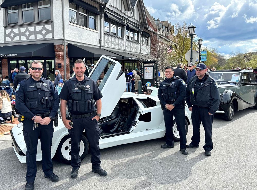 Four officers standing next to a white car